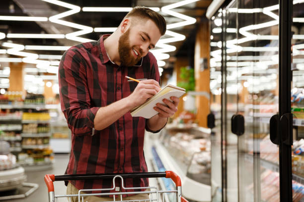 istock Happy young man in supermarket talking by phone writing notes 1353861706