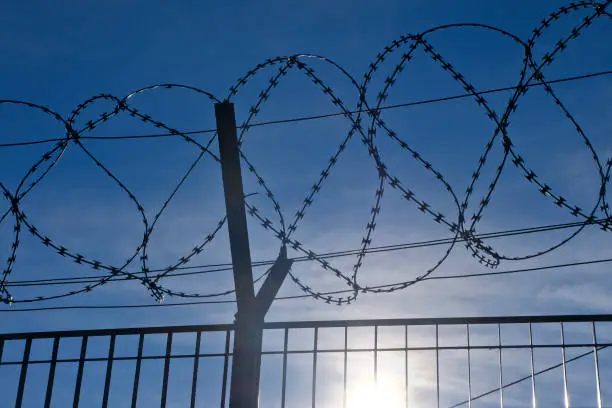 The Fence - Low sun behind razor wire (NATO-Draht). Symbol of hope for a better future.