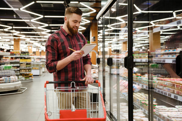 istock Happy young man standing in supermarket reading notes 1353863114