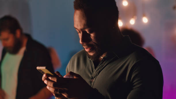 istock Black male texting on cellphone during party 1353863594