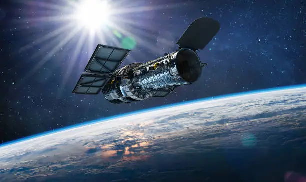 Photo of Hubble telescope on orbit of Earth. Space observatory. Telescope in outer space near surface of blue planet. Stars and sun. Elements of this image furnished by NASA