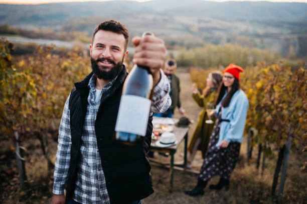 the young owner of the winery holds a bottle of wine - aging process french culture winemaking next to imagens e fotografias de stock