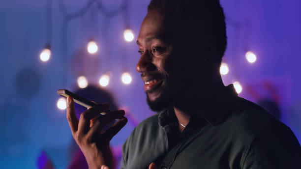 istock Glad black man communicating via audio messages during night party 1353865644