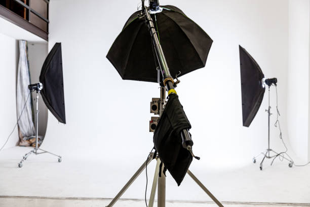 istock Empty photo studio with lighting equipment. Photographer workplace interior with professional tool set gear. Flash light white background scenes ready for studio shooting. Modern photographer studio 1353868749