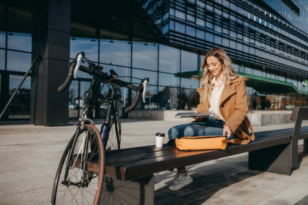 Businesswoman typing on a computer with her bike outside the office