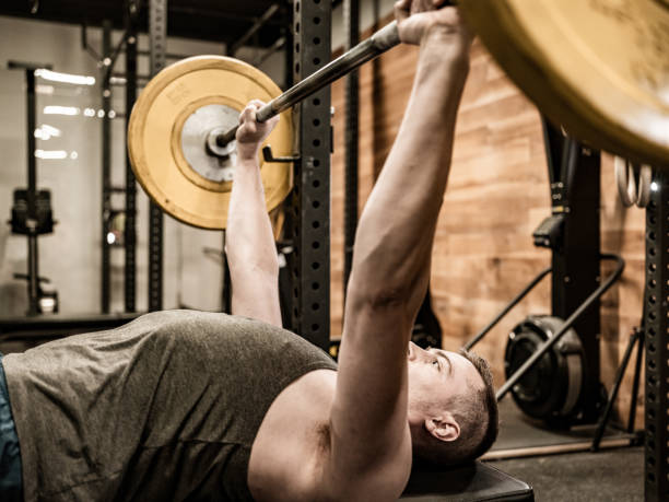 istock Young Man lifting weights in the Gym 1353874180
