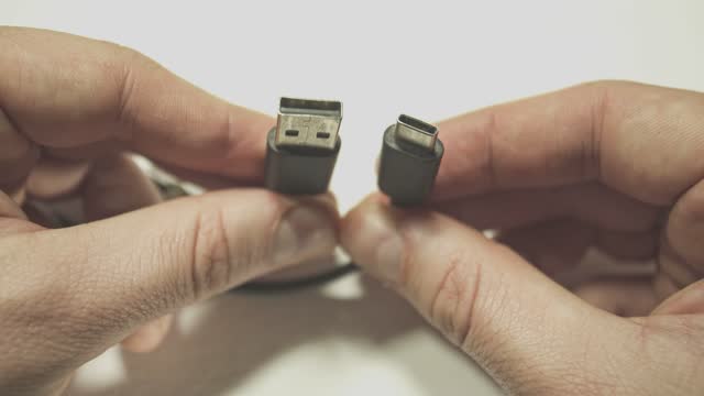 Comparison of USB-A and USB-C connector system or connection interface in hand isolated on background