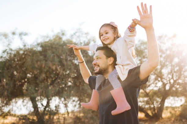 istock Young father carrying daughter on shoulders  in nature 1353875193
