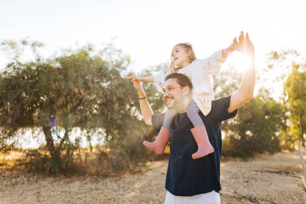 istock Young father carrying daughter on shoulders  in nature 1353876299