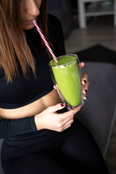 istock Unrecognizable woman drinking a green smoothie at home before her workout 1353878757