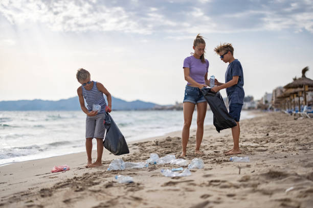 istock Three kids cleaning up the beach 1353880327