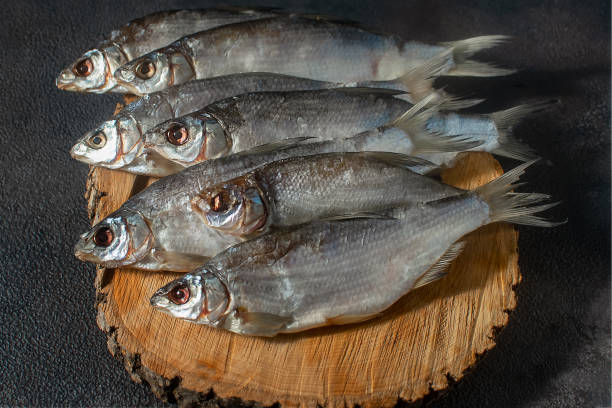 istock Dried dry silver bream fish, laid out against a dark background, close-up 1353883122