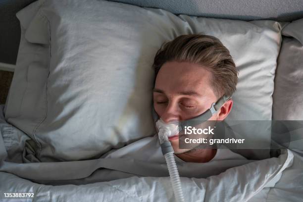 Close Up Of A Young Man With Sleep Apnea Wearing A Cpap Mask In Bed Sleeping On His Side Stock Photo - Download Image Now