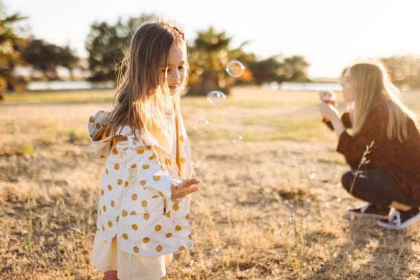 istock Young mother and daughter having fun in park with Soap Bubbles 1353884328
