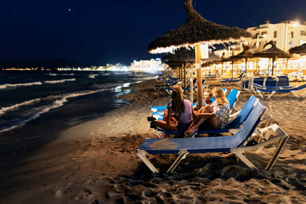 мама и дети сидят на пляже ночью - teenager parent beach contemporary стоковые фото и изображения