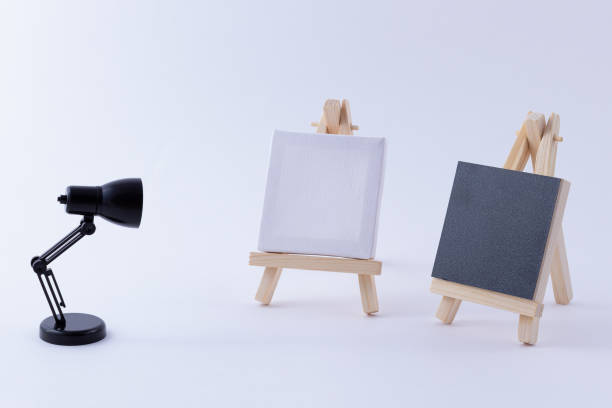 istock Two Wooden Easels Miniature with Blank Black and White Square Canvas and Table Lamp 1353887203