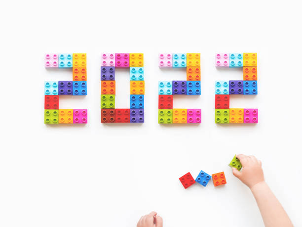 istock 2022 New Year. Child is playing with colorful constructor blocks. Kid's hands with bricks toy on white background. Educational toy, flat lay, top view. 1353888251