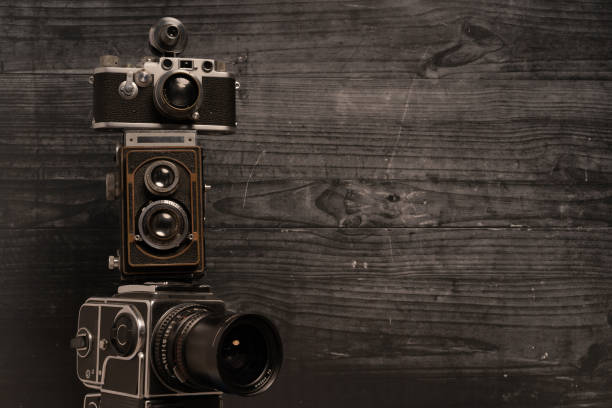 Three stacked vintage cameras on a dark wood background