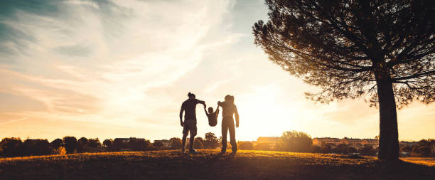 silhueta de família feliz caminhando no prado ao pôr do sol - mãe, pai e filho se divertindo ao ar livre curtindo um tempo juntos - família, amor, saúde mental e conceito de estilo de vida feliz - family child mother autumn - fotografias e filmes do acervo