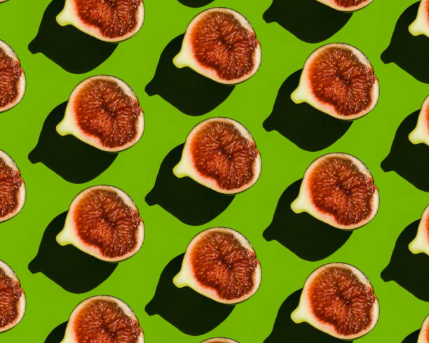 istock Pattern of ripe figs in a cut on a green background. 1353895509