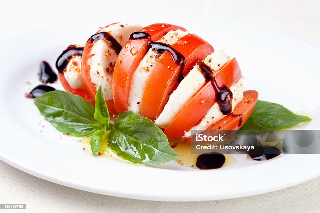 Caprese salad Caprese salad Tomato and mozzarella slices with basil leaves on white background Basil Stock Photo