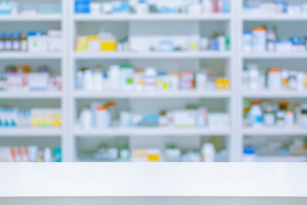 istock Empty white counter with pharmacy drugstore shelves blurred background 1353898747