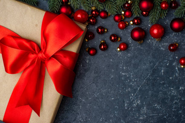 istock Red christmas balls, gift box and christmas tree on the black stone background 1353910001