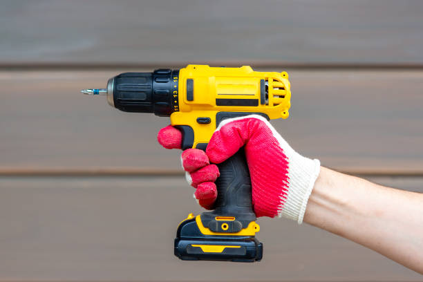 istock Electric screwdriver in hand on wooden background 1353931446