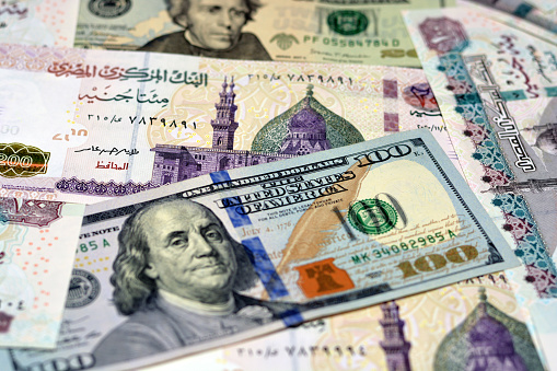 Egyptian money and American dollars banknotes background, various Egyptian pounds and American dollar bills, selective focus, 200 pounds, 100 pounds, 100 dollars bill and 20 dollars bill