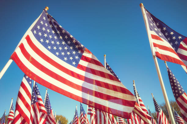 istock American flags waving in the wind against blue sky 1353936917