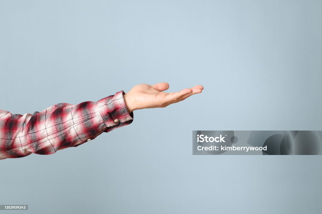 Hand in Blue The Asian man hand with plaid shirt showing on the blue background. Men Stock Photo