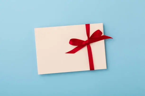 Letter with red bow ribbon on blue background, flatlay