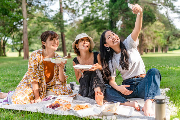 Friends taking selfies while enjoying having picnic in nature