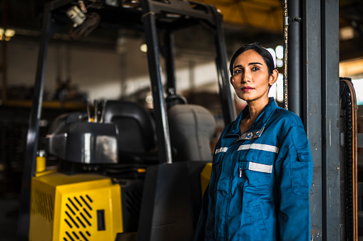 Industrial Portrait of Indian Female  Factory Worker in front of forklift