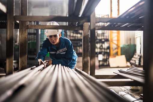 Female Steel Factory Worker at work moving steel poles