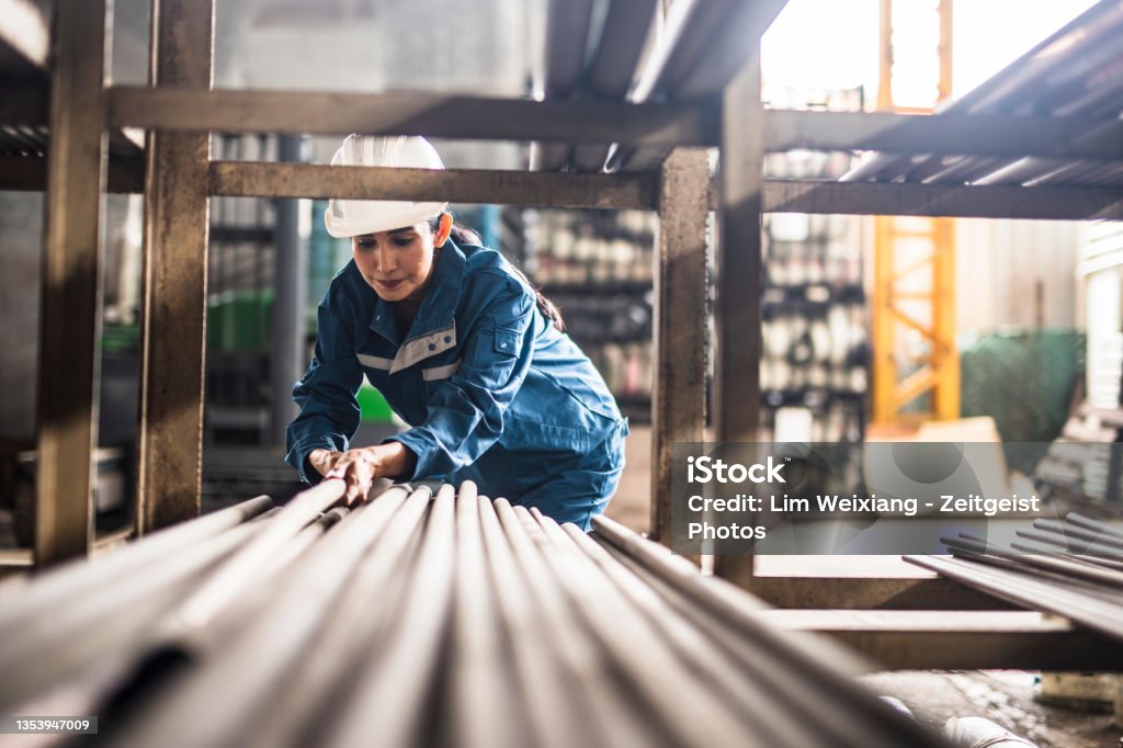 Female Steel Factory Worker at work Female Steel Factory Worker at work moving steel poles Occupation Stock Photo