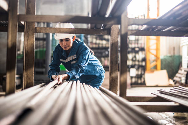 Female Steel Factory Worker at work Female Steel Factory Worker at work moving steel poles blue collar worker photos stock pictures, royalty-free photos & images