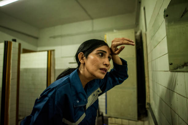Indian Female factory worker in toilet looking at mirror stock photo