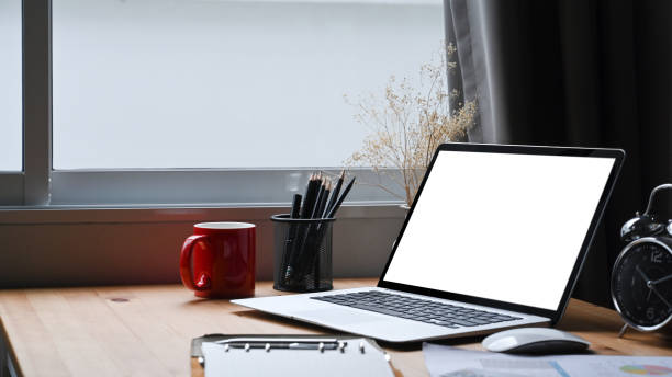 istock Mock up computer laptop with empty display, coffee cup and pencil holder on wooden table. 1353948637