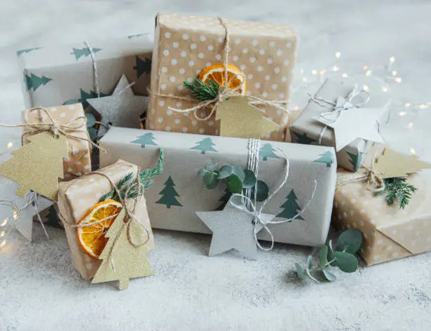 Christmas  decorative homemade gift boxes wrapped in brown kraft paper on a gray concrete background