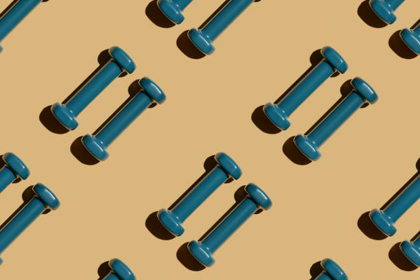 istock Two blue fitness dumbbells on a beige background lie parallel, pattern, top view, close-up. 1353952288