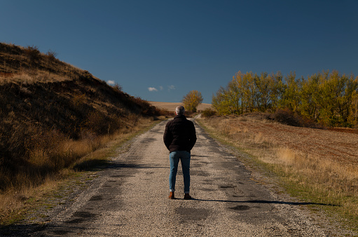 Portrait of adult man in winter cloth on a country road against blue sky. Shot in Castilla y Leon, Spain