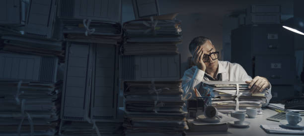 istock Exhausted businessman working overtime in the office 1353953208