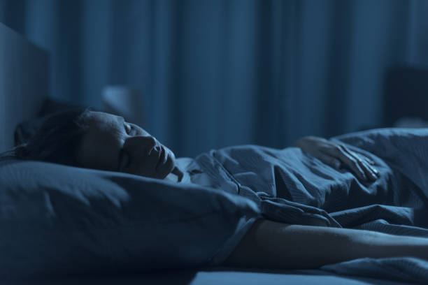 woman sleeping in her bed at night - deitando imagens e fotografias de stock