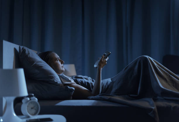 istock Woman lying in bed and watching TV 1353954676
