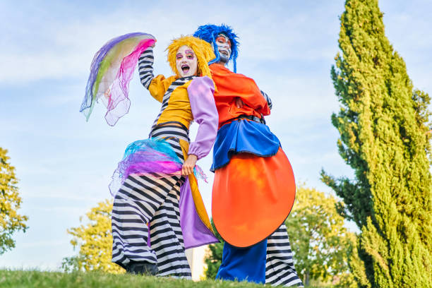 istock Positive clowns standing back to back during masquerade in park 1353956648