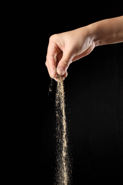 istock Hand sprinkling ground pepper isolated on black background 1353957153