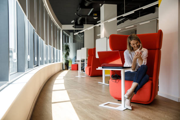 istock Cheerful businesswoman reading a text message on smart phone while taking a break from work 1353959269