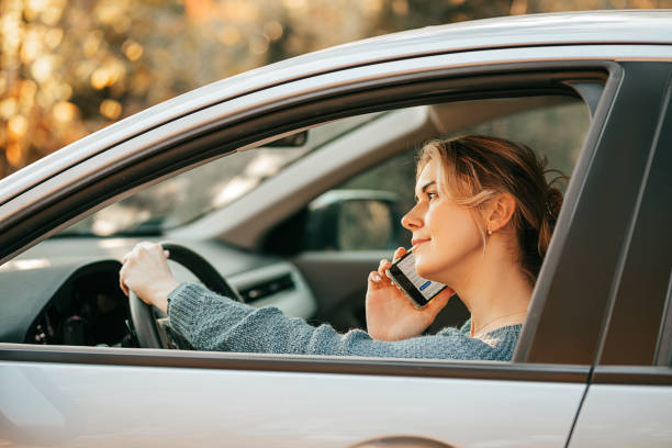 foto di giovane bella donna guida l'auto, viola le regole del traffico, si distrae, guarda lo schermo del telefono cellulare, usa lo smartphone, il concetto di vita moderna frenetica - car phone foto e immagini stock