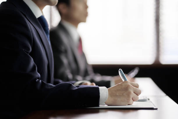 in den händen eines asiatischen geschäftsmannes, der einer präsentation bei einem meeting zuhört - business studies stock-fotos und bilder